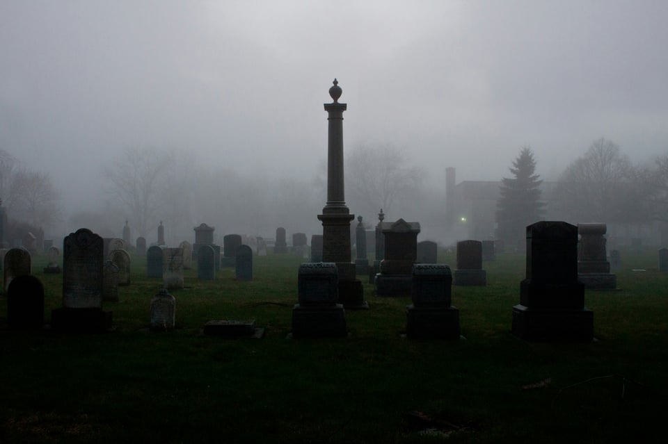 A foggy cemetery in the dark distance