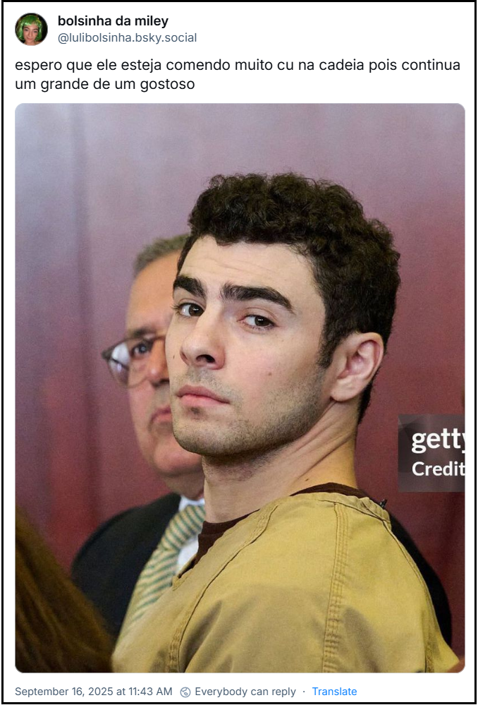 Post de bolsinha da miley (@lulibolsinha.bsky.social) com o texto: espero que ele esteja comendo muito cu na cadeia pois continua um grande de um gostoso (imagem de Luigi Mangione, com cabelo escuro encaracolado e barba rala. Ele está a olhar diretamente para a câmara com uma expressão séria, veste uma peça de roupa de cor cáqui ou castanho claro, vestuário da prisão. No fundo, ligeiramente desfocado, vê-se um homem mais velho, de óculos e fato e gravata, parcialmente visível atrás de Mangione. O ambiente é de dentro do tribunal, com uma parede avermelhada ao fundo. Há uma marca d'água no canto inferior direito da imagem, está visível “getty" e a palavra "Credit".