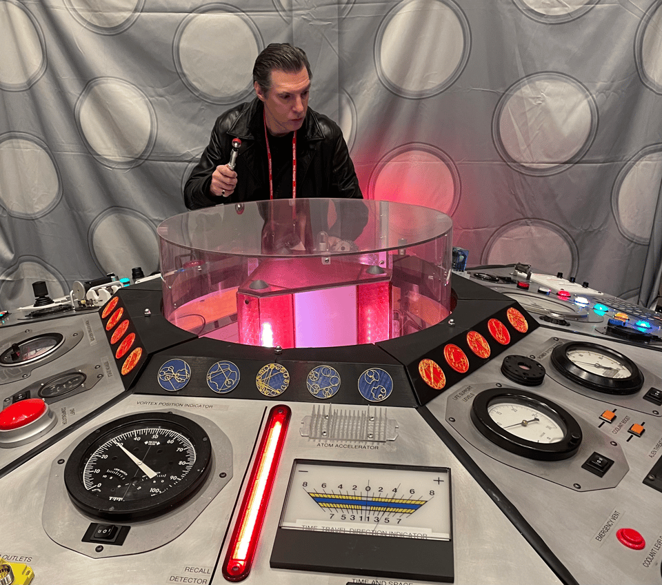 A man at the controls of a dense sci-fi control panel