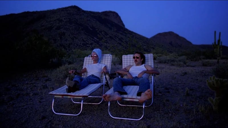 A shot from Raising Arizona of Holly Hunter and Nicholas Cage reclining on lawn chairs in the Arizona desert.