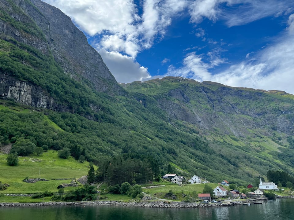 Houses next to water in front of fjord in Norway