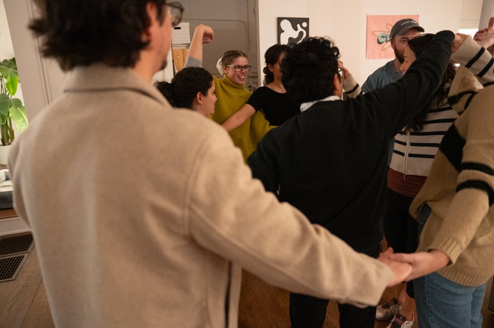 People holding hands in a tangle, following standard procedure for earning five stars.