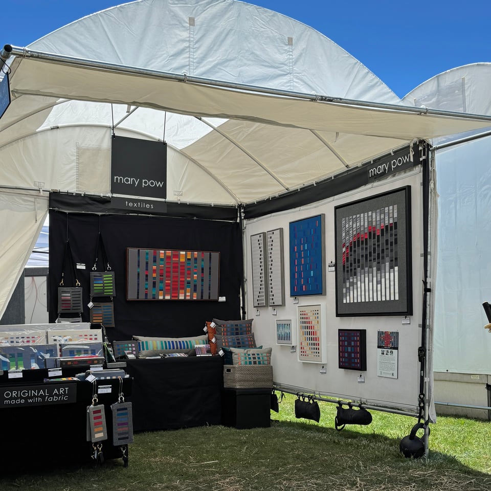Mary Pow's art fair booth with her textile artworks, pillows, and handbags