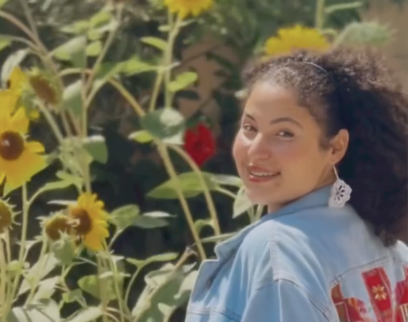 a picture of wizard bisan wearing a jean jacket in front of sunflowers