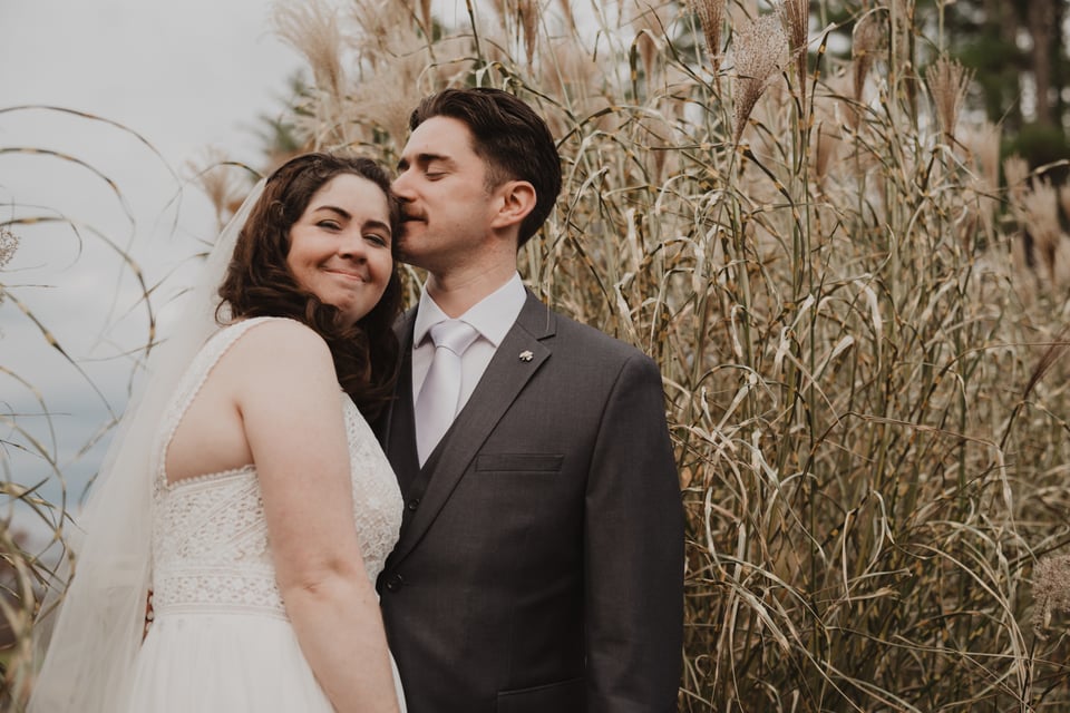 a bride and groom in front of tall grass