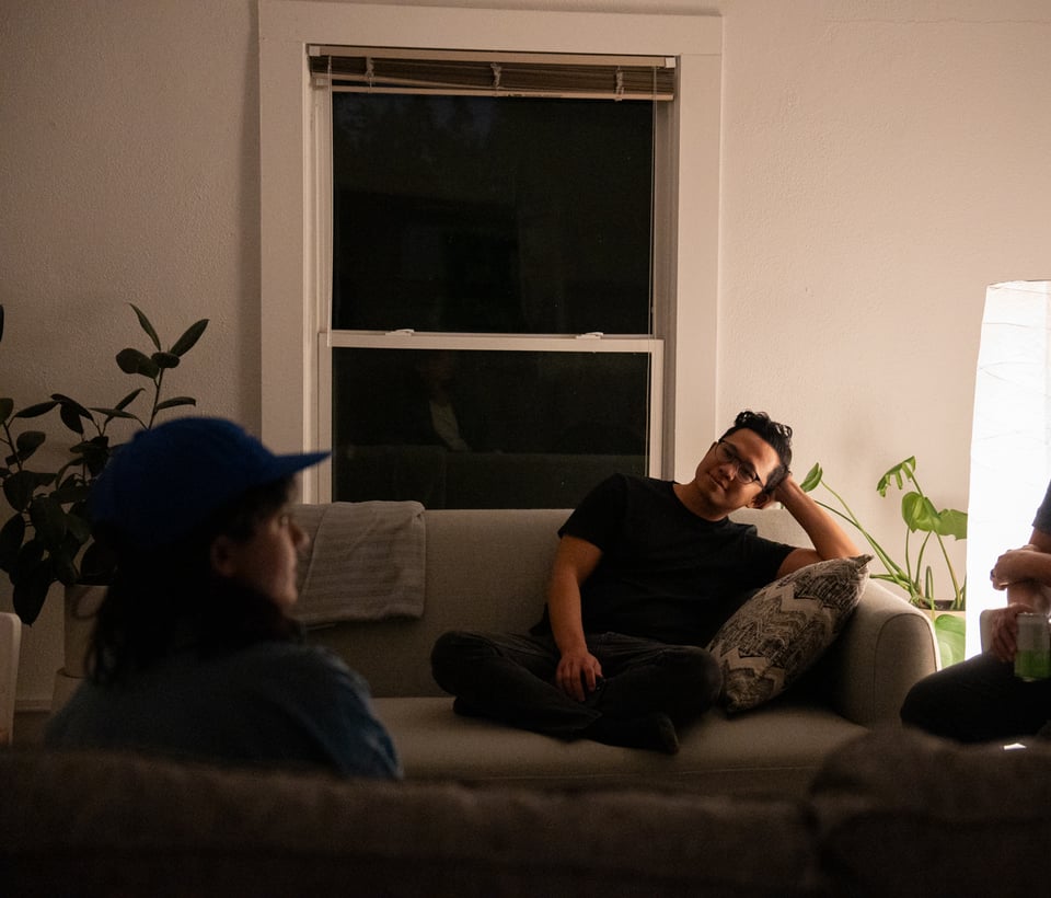 A lamp-lit room with people talking.
