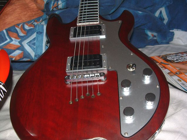 A red guitar on a bed