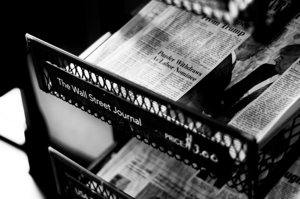 A black-and-white photo of a newspaper in a rack, with the label 'The Wall Street Journal'. Photo by Philip Strong on Unsplash
