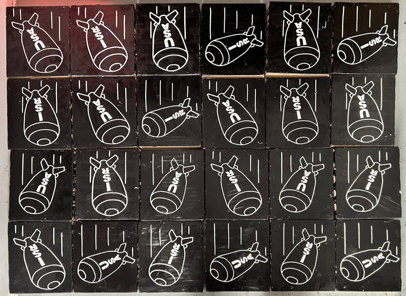 24 paintings of falling bombs labeled USA and ISR.