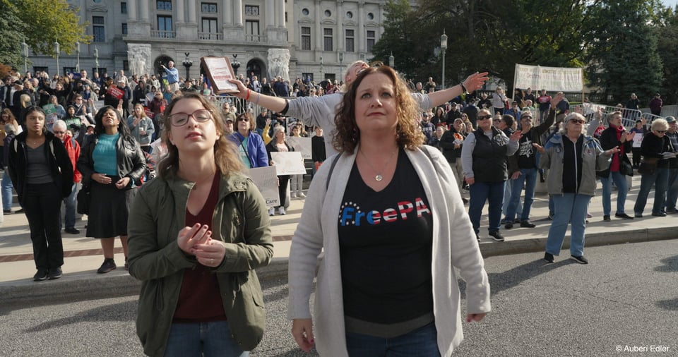Image of a woman wearing a FreePA shirt stands beside her daughter. They are at an event at the Pennsylvania capitol about conservative Christian values.