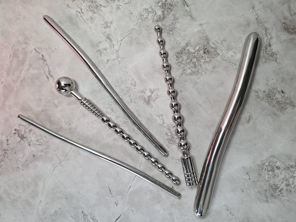 five steel sounding rods lying on a marble counter