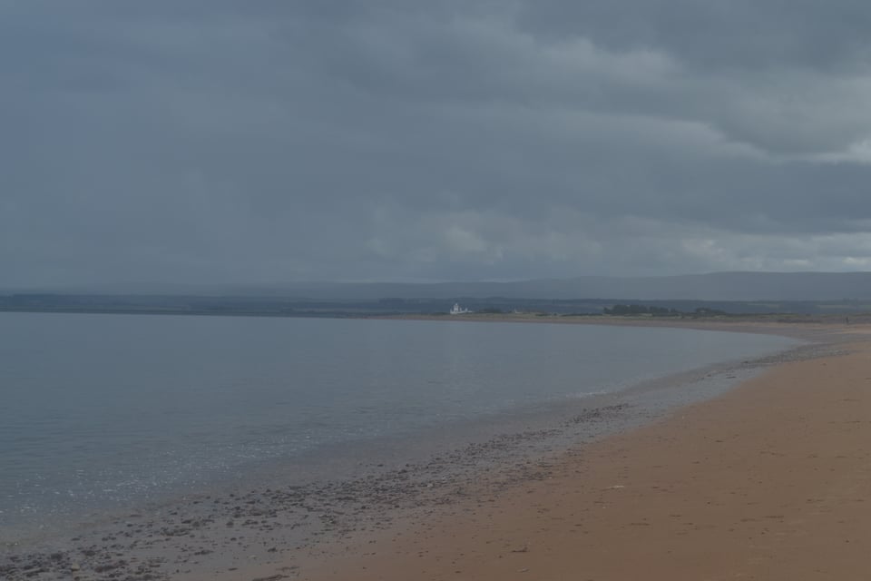 A curved beach of deep yellow/gold sand, around a very quiet bay.