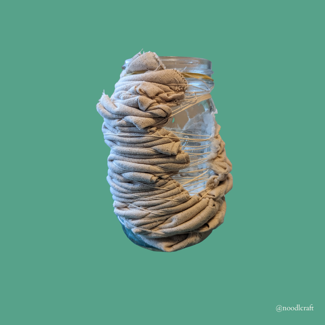 Cotton muslin wrapped around a mason jar, and tied down with twine. 