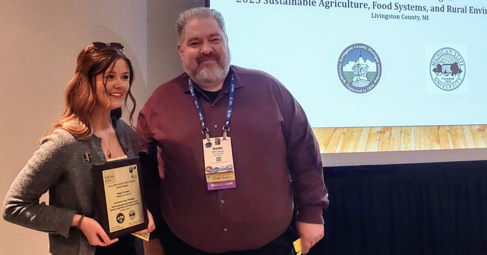 Abigail Carrigan presented with the American Planning Association award on April 27, 2026. She is holding a plaque, standing with the Chair of the American Planning Association - Small Town & Rural Planning Division.