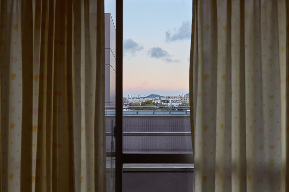 The view from the hospital room. A mountain framed by curtains and a window. Balcony at the front.