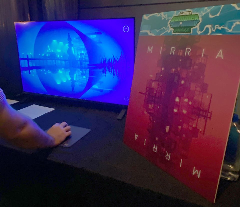 Someone playing Mirria on a tv next to a Mirria poster sign