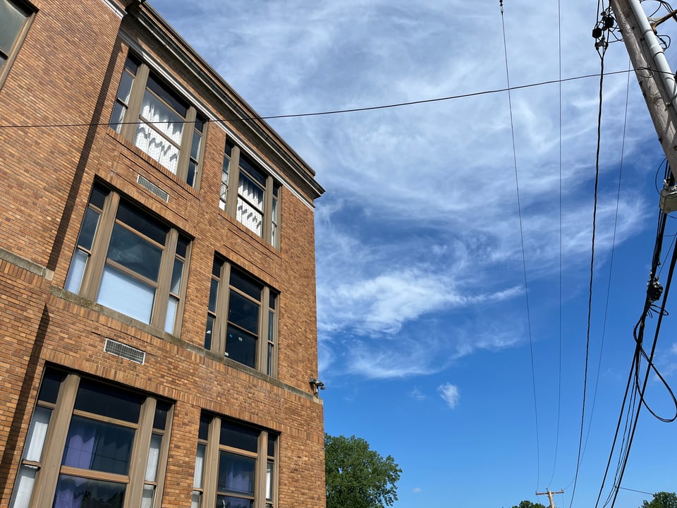 A shot of the corner of an old school building against a very blue sky with wisps of cloud