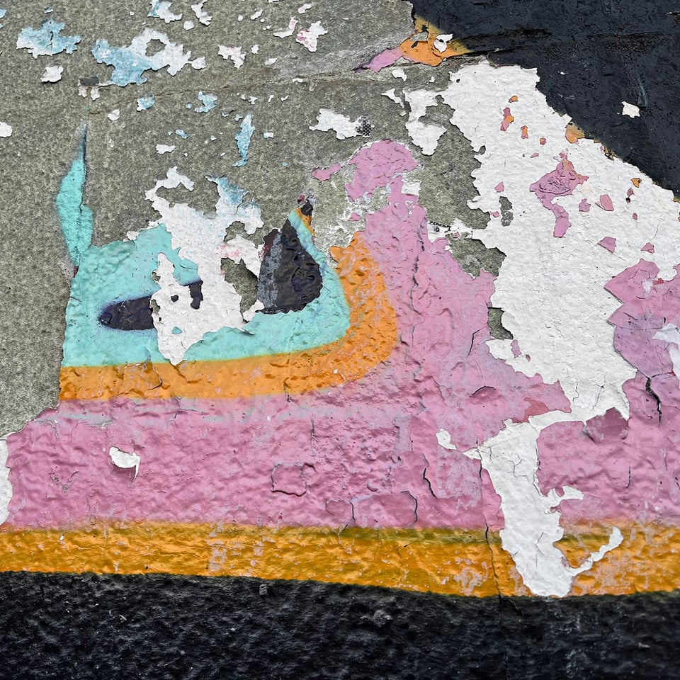 Scrapes and remnants of graffiti on a wall.