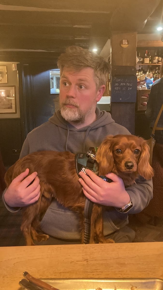 An old man with a young dog in his arms.