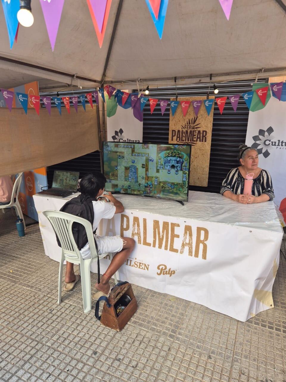 A younger person playing Arranger on a TV in a street fair booth