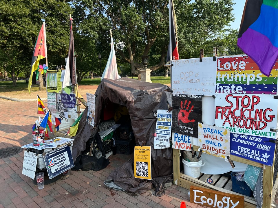 Photo of 1-person shelter in Lafayette park, covered with posters and slogans for social justice