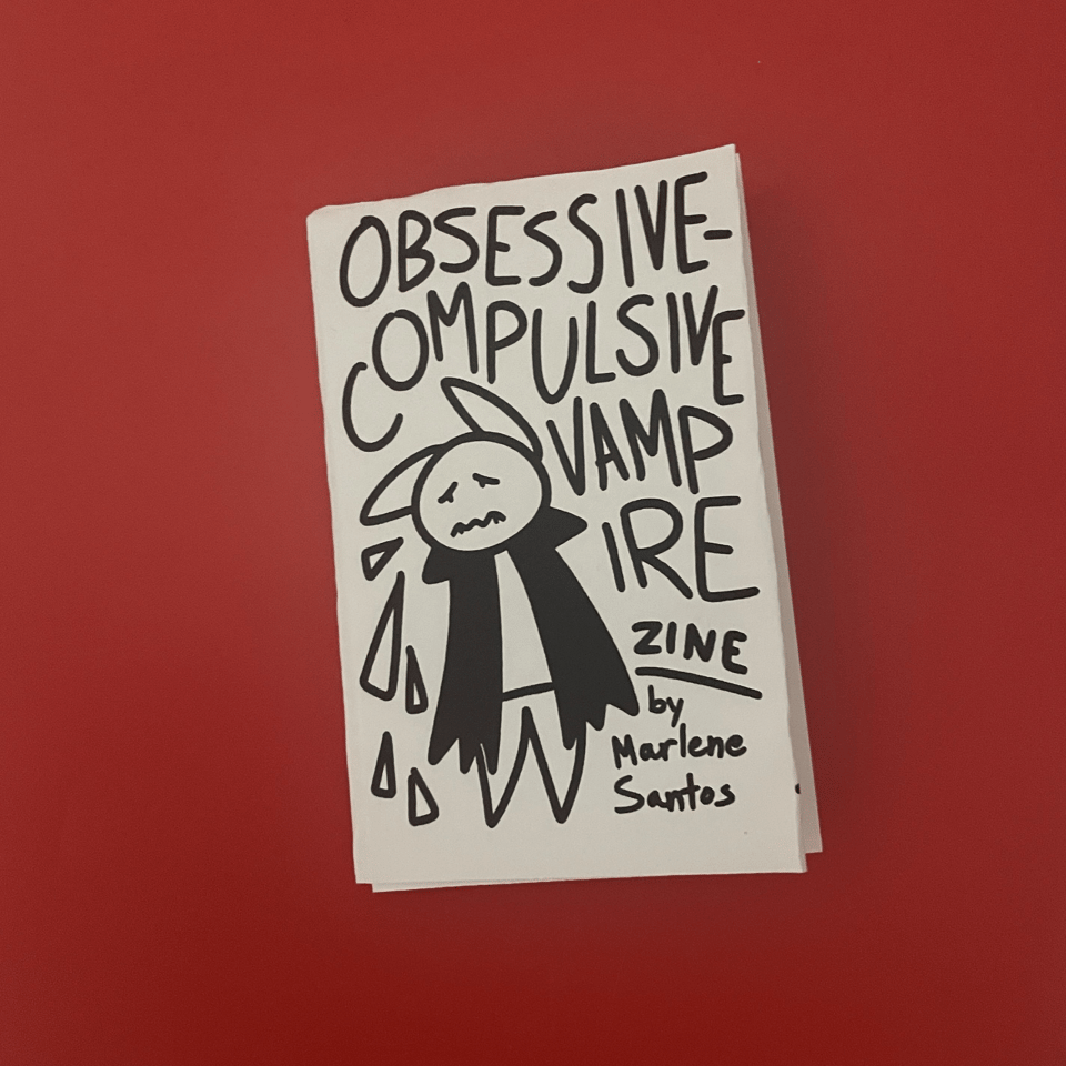 An 8-page zine with a cover that reads "Obsessive-Compulsive Vampire Zine by Marlene Santos." The cover has the text crowding around a bat-like creature in a cloak who looks really worried.