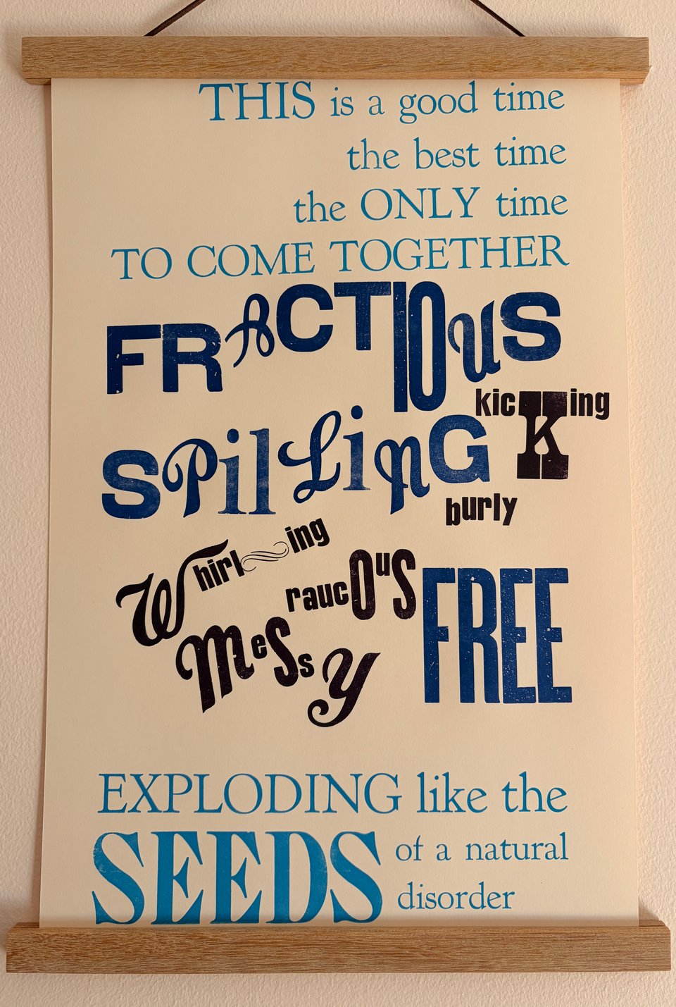 Letterpress print in many shades of blue on cream paper with a wide range of playful type. The text reads: "THIS is a good time
the best time
the ONLY time
TO COME TOGETHER
Fractious kicking spilling whirling burly raucous messy FREE
Exploding like the SEEDS of a natural disorder"