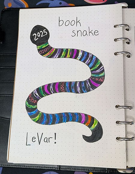 a drawing of a snake with 40 colorful stripes alternating with black stripes. The snake's head says 2025, and handwritten text at the top says "book snake" and at the bottom "LeVar!" (which is the snake's name, after LeVar Burton from Reading Rainbow, of course)