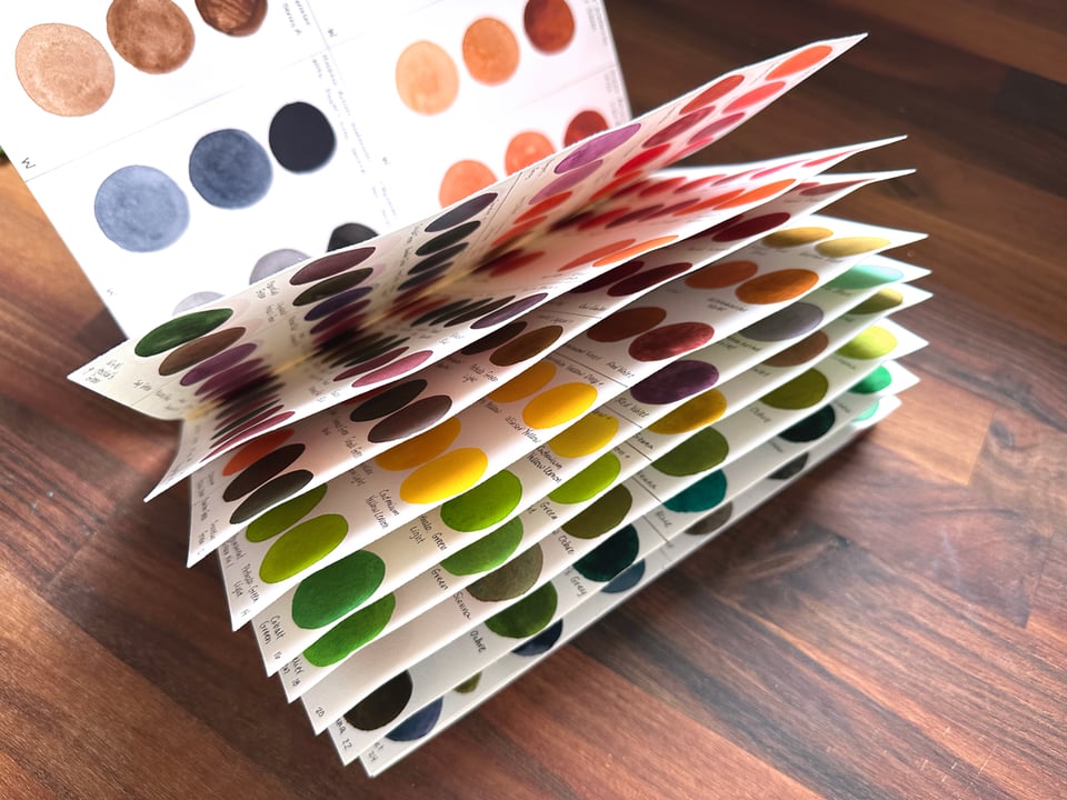 A swatch book with the pages splaying up and out, revealing dozens of color samples inside.