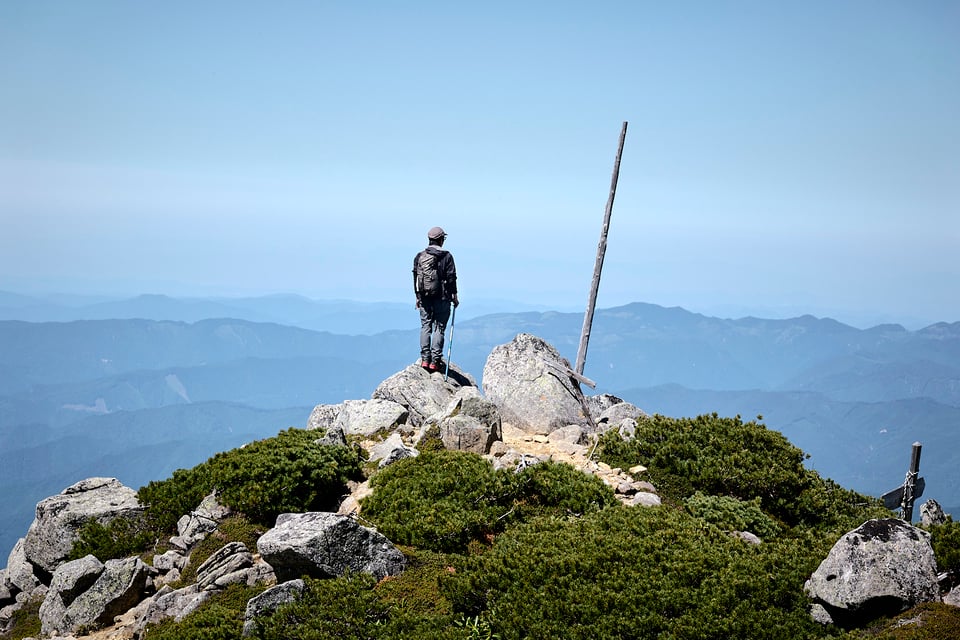 A hiker stands on the summit of Kisomaedake.
