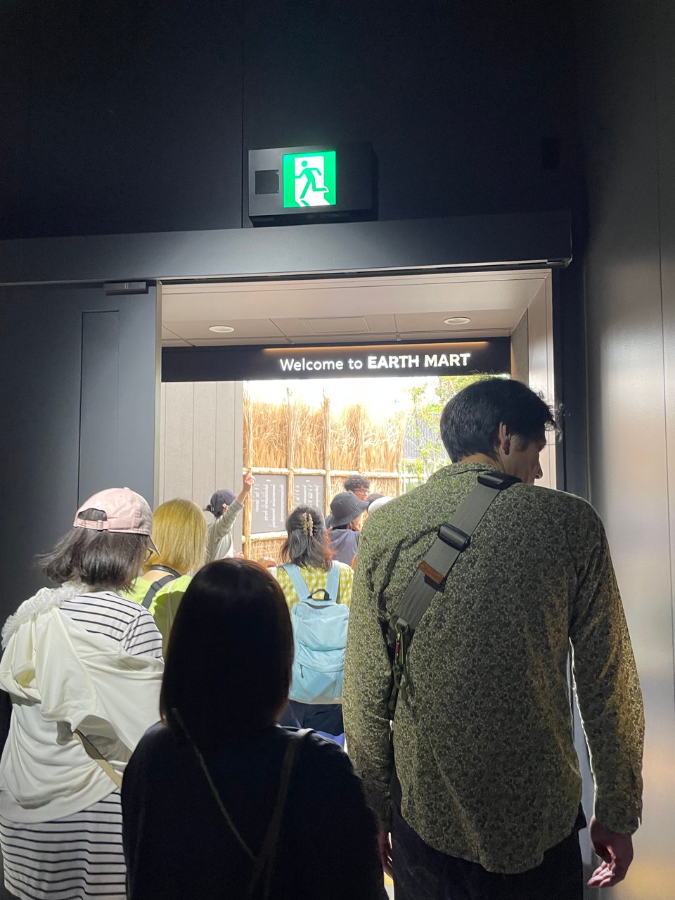 A crowd moving through the exit door of the Earth Mart pavilion. Above the exit is a clever sign reading "Welcome to Earth Mart."