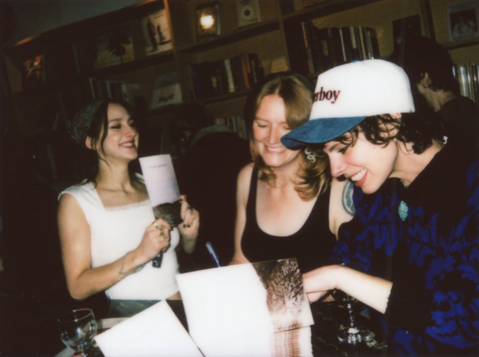 taylor grins and holds up "how the light gets in" while tallen and beth sign copies