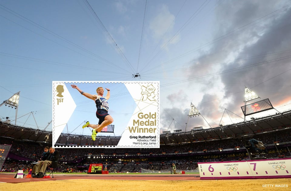 A wide-shot photograph of a long jump athlete in mid air over the sand in which he will land. In the background is an athletics stadium at dusk with the floodlights turned on. The athlete is framed in a postage stamp, on which is written,