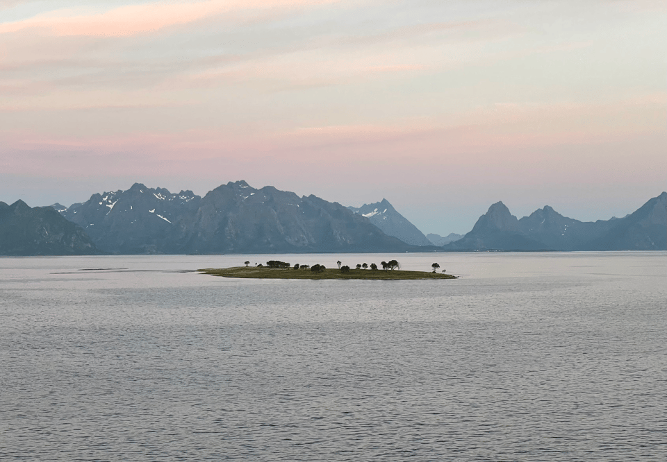 A small isolated island with snowy mountains in the distance