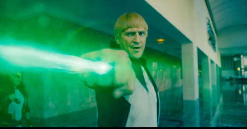 Nathan Fillion as Guy Gardner, giving his biggest dumbass look to accompany his idiot bowlcut, as he fires a beam out of his power ring. Hawkgirl is close behind him.