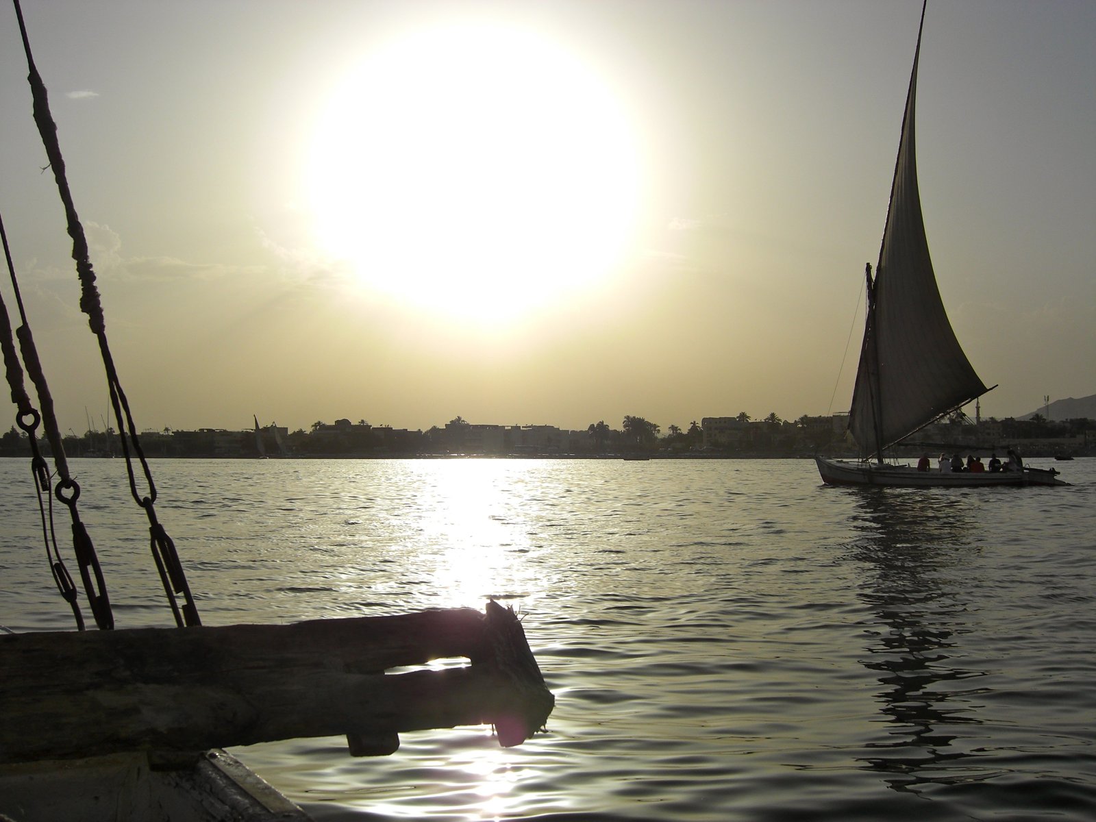 A felucca silhouetted against the sunset on the Nile, with another sailboat in the distance
