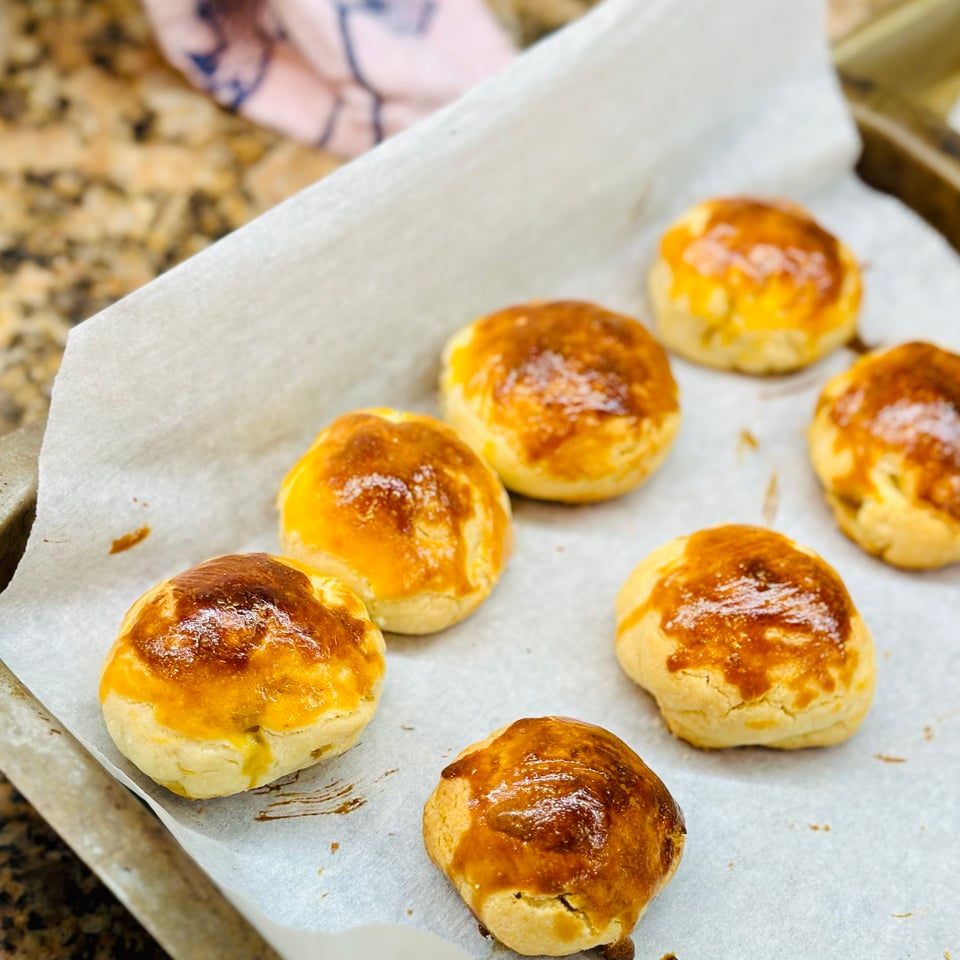 A photo of closed pineapple tarts shaped like golf balls, with an egg wash on it