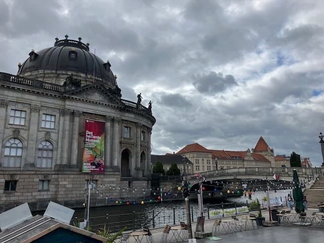Domed stone building on a river under cloudy sky