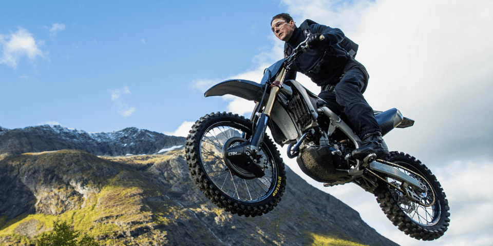 Tom Cruise rides a motorbike off a cliff.