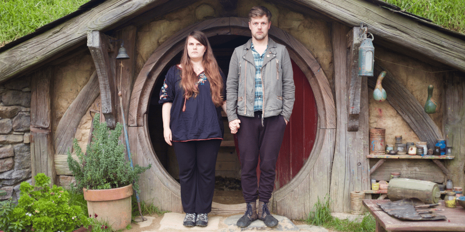 The Meads stand in front of a hobbit hole.