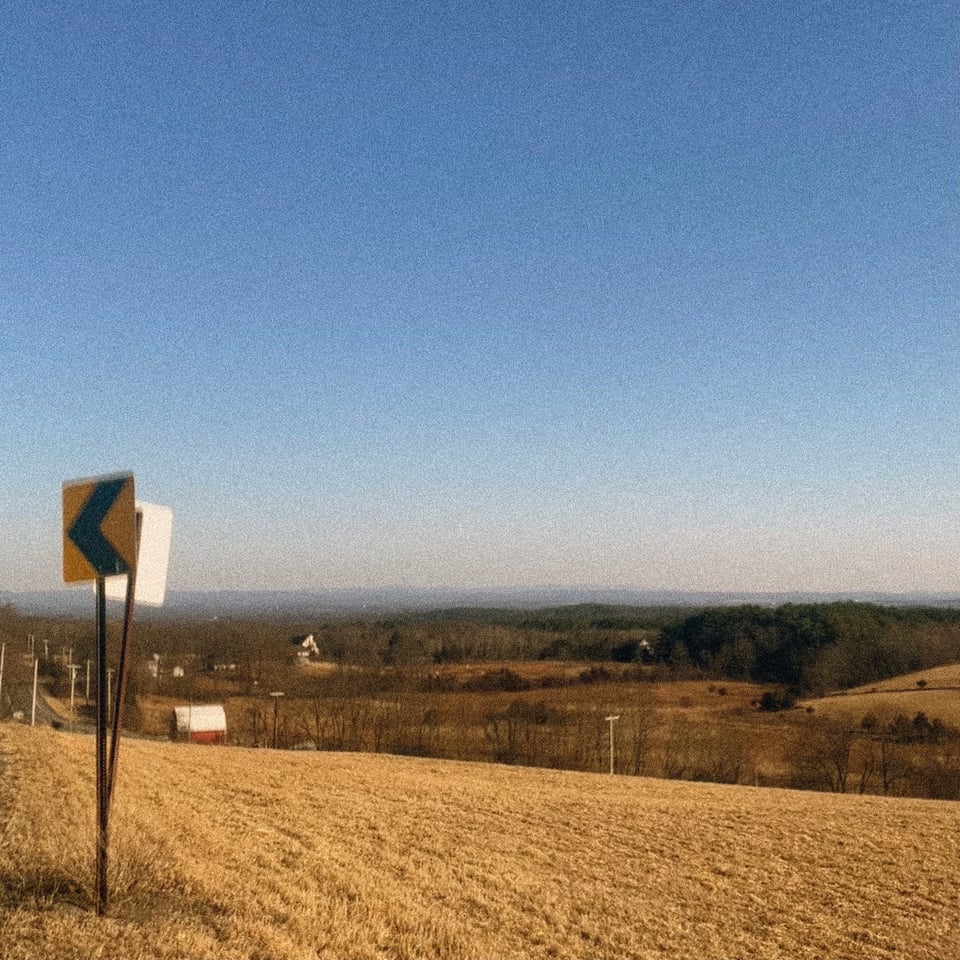 on the first day that felt like spring in the Hudson Valley two road signs wobble in the breeze overlooking a beautiful if quite parched view of the valley