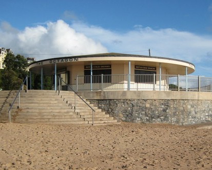A single storey octagonal building with a low pitched roof and a wide verandah held up with slender pillars. The whole is build on a circular platform as part of the sea wall. On one side steps lead down to the sandy beach.