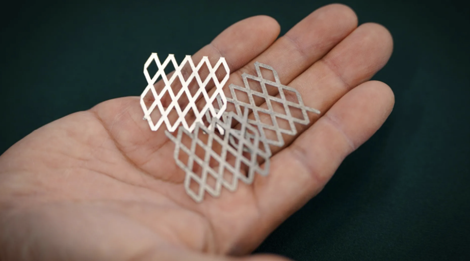 A hand holding small pieces of diamond-perforated stainless steel