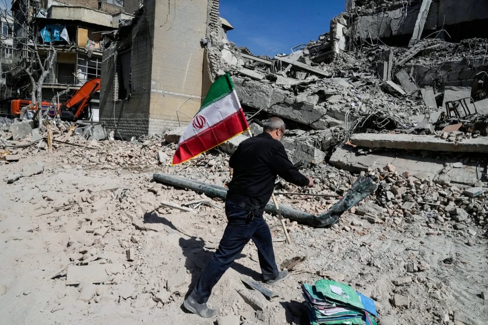 A man carries an Iranian flag to place on the rubble of a police facility struck during the US- Israeli military campaign in Tehran on Wednesday.