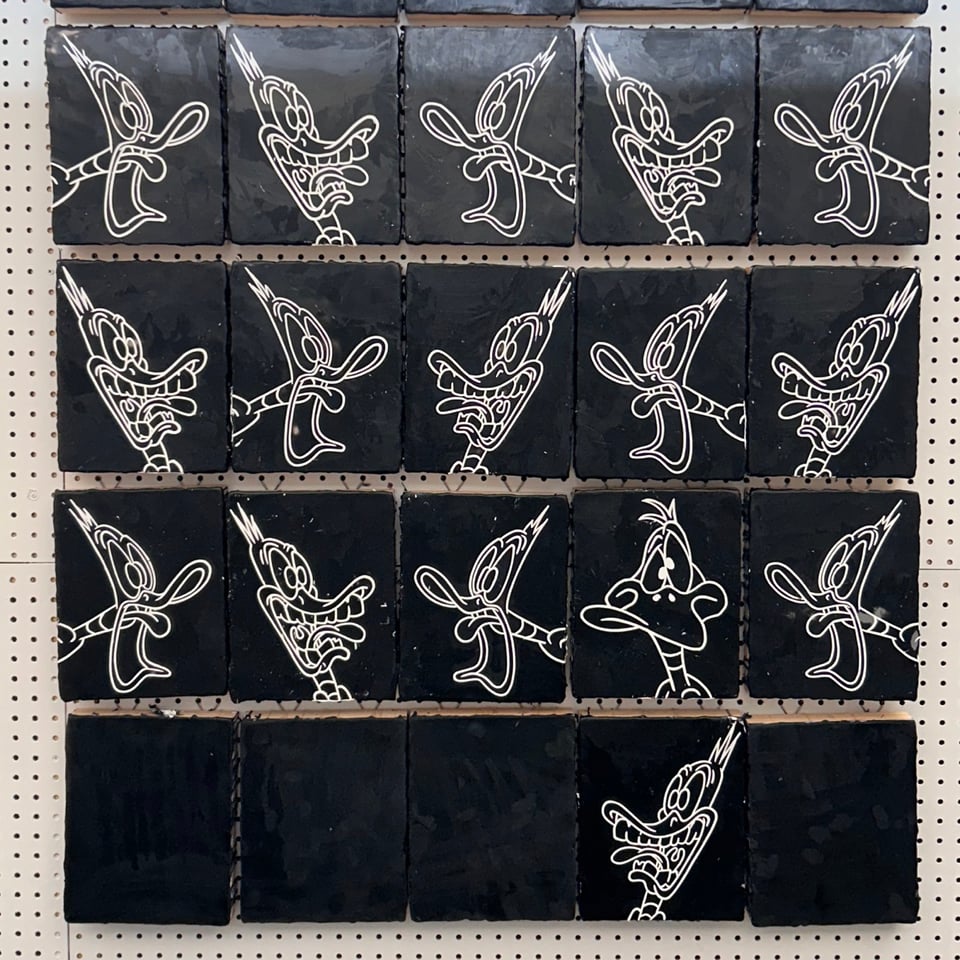 Small black panels filled with screaming ducks in white outline on a pegboard wall.
