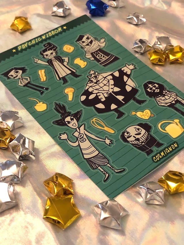A photo of the Psychic Wisdom sticker sheet, showing the 7 Psychonauts Founders along with various items related to their interests. It's on a holographic fabric surface, surrounded by shiny paper stars.