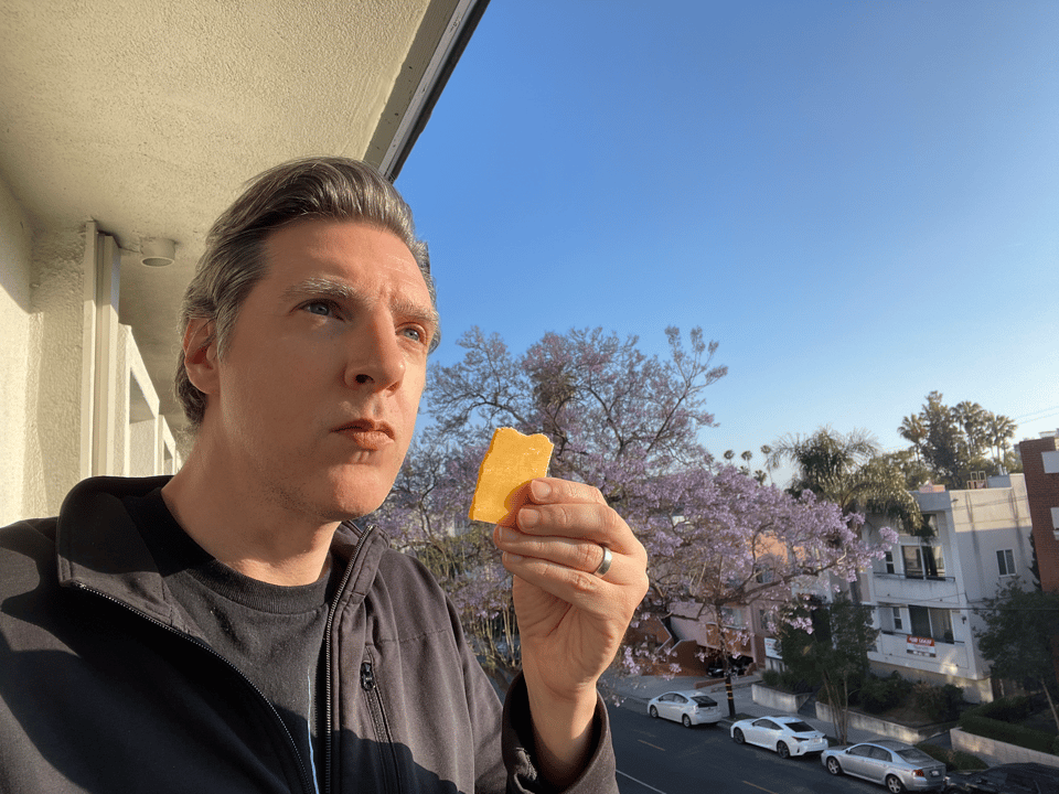A person stares at the big horizon while holding a small piece of cheese