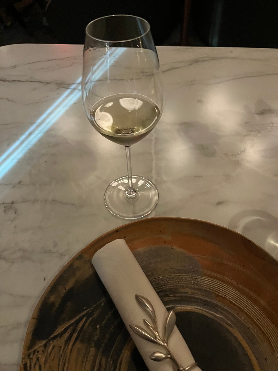 A glass of champagne and a beautiful place setting, with a napkin holder that looks like it's straight out of the fairy realm (complimentary)