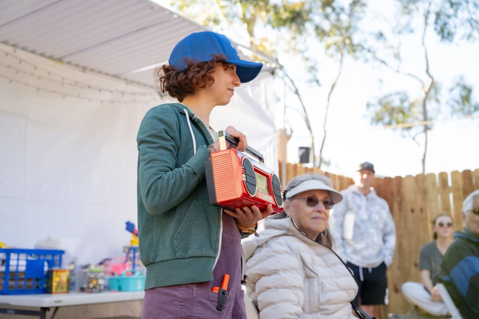 A young girl in a baseball cap holding a boombox