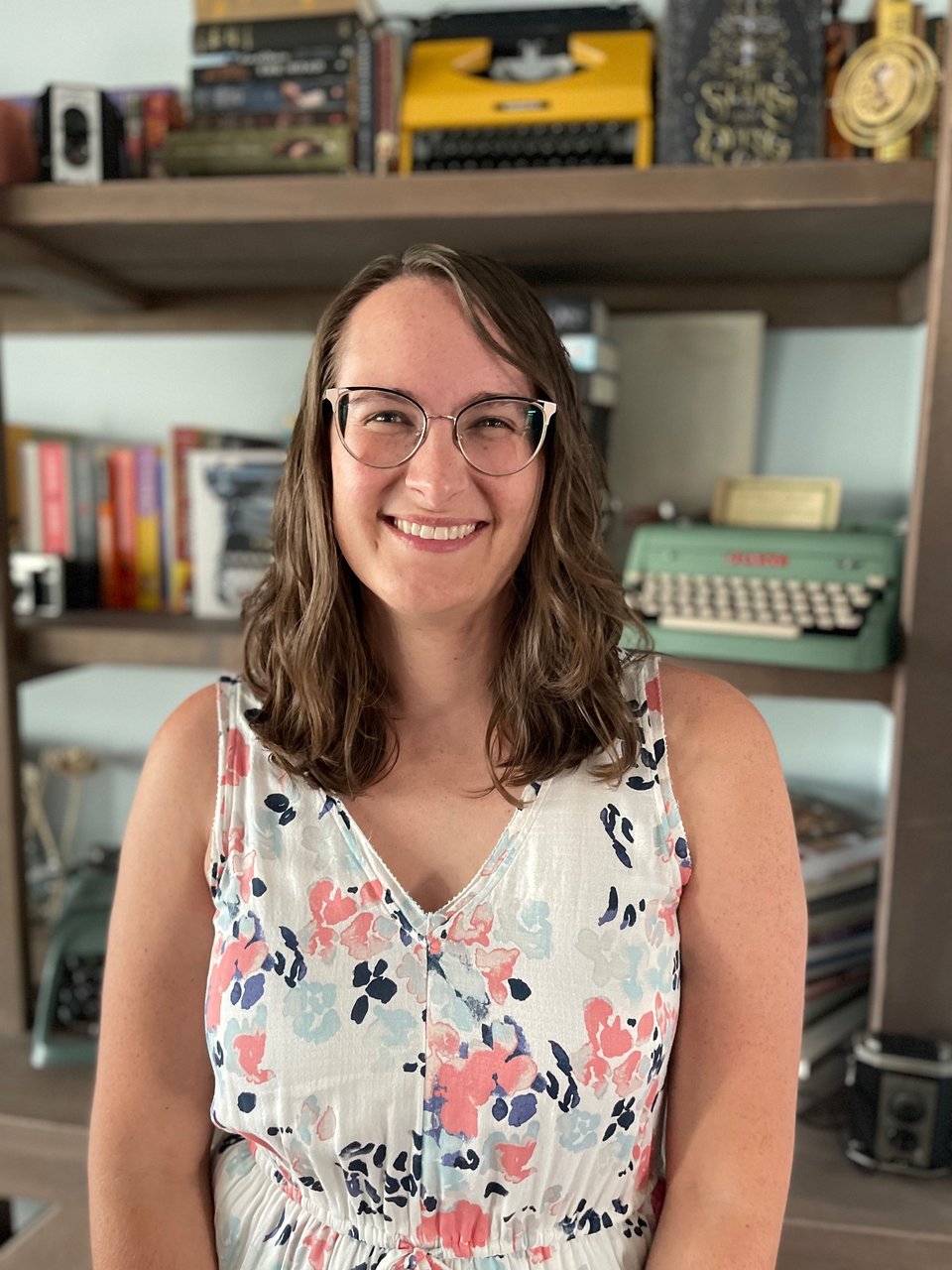 A photo of Haley Donoghue in front of a shelves holding books and typewriters.
